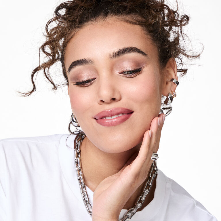 A brunette model with curly hair wearing the All Eyes on Hue look soft smiles while looking down.